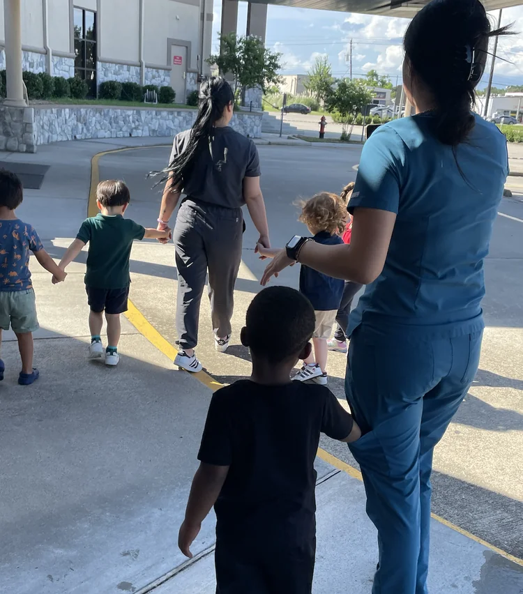 Child care teachers guiding preschool children in line outside daycare in Webster Texas