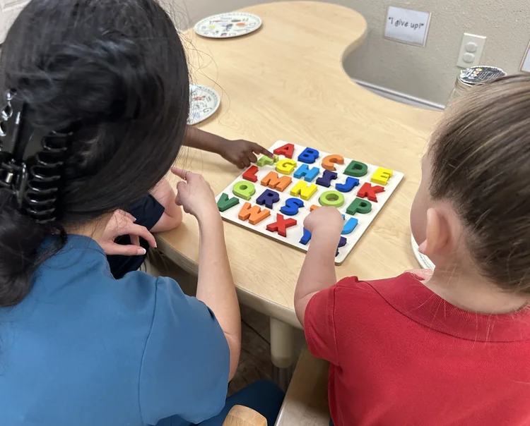 Children reviewing alphabet letters on classroom bulletin board during preschool activity at daycare